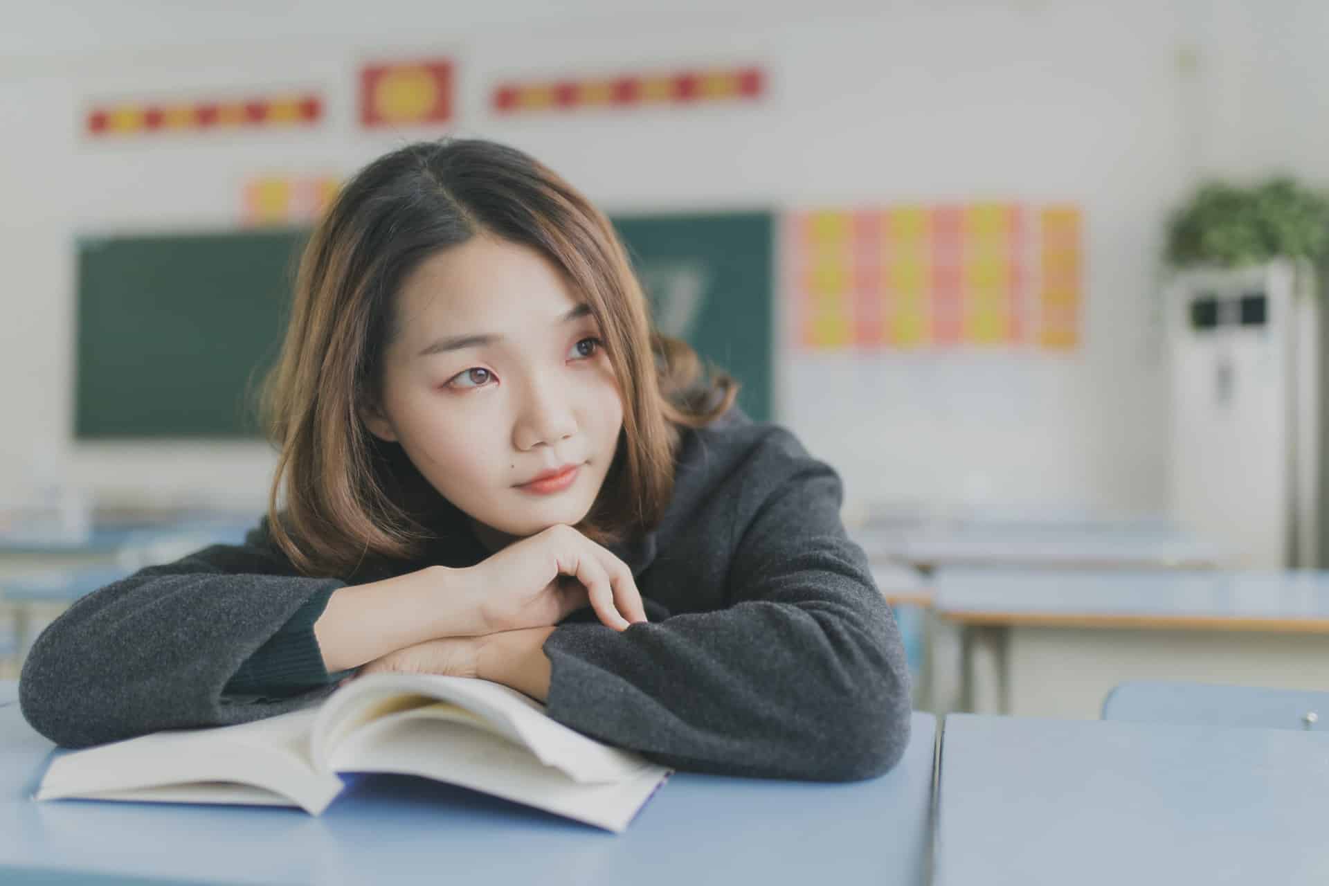 Girl studying with a concerned expression, surrounded by books and papers
