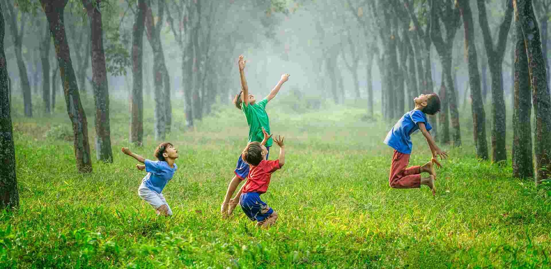 Children playing together in a sunlit field, symbolising joy, confidence, and the development of self-esteem through connection and play.