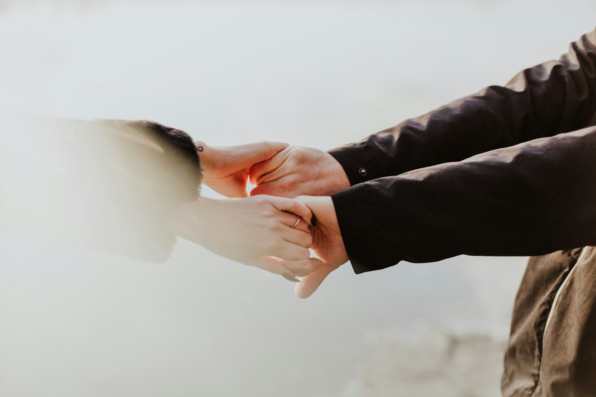 Two people holding hands during a difficult moment, representing emotional support through online divorce counseling and therapy.